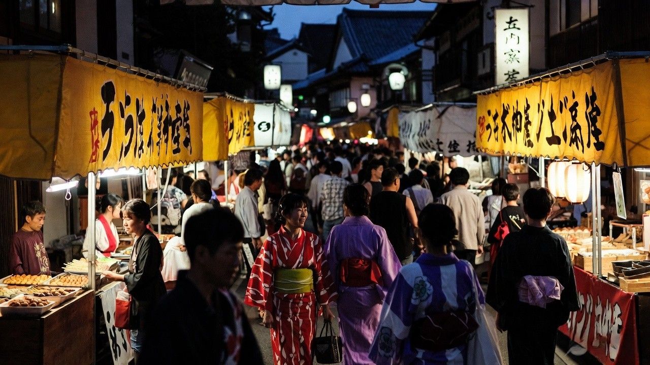 Gion Matsuri food stalls with people in yukata walking through yoiyama street market Kyoto