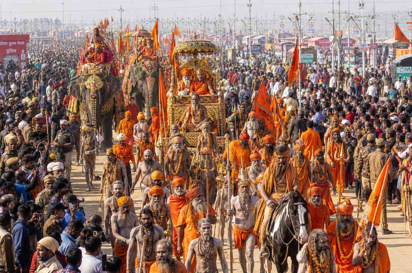 Grand Akhara procession at Kumbh Mela with sadhus in saffron robes marching with tridents flags and decorated elephants