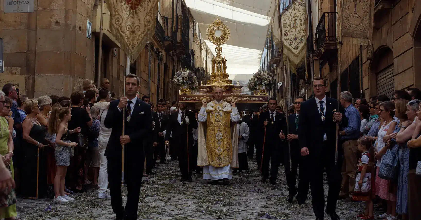 Corpus Christi Festival 2026 procession through narrow cobblestone streets in Toledo Spain with gold monstrance being carried by clergy