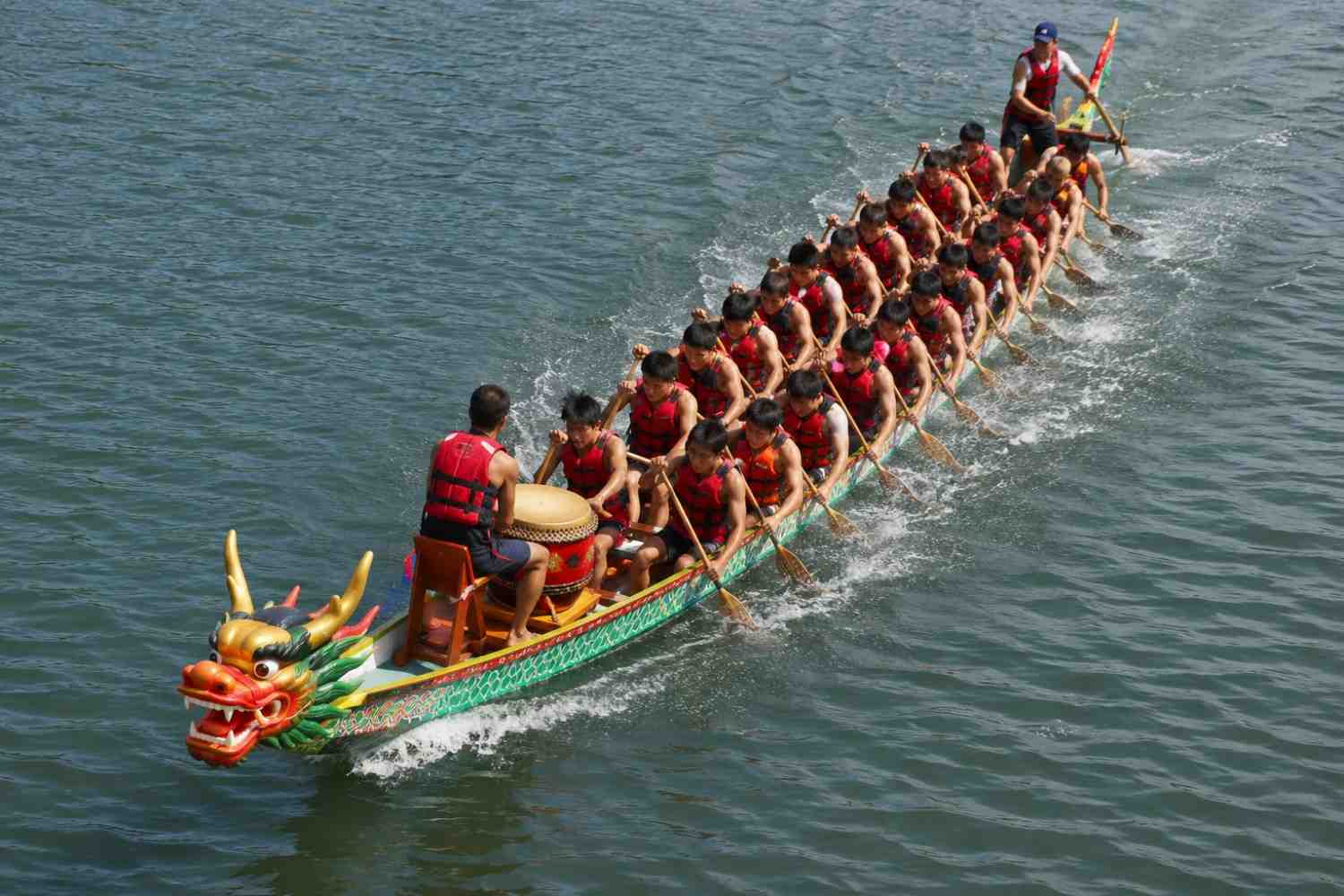 Twenty paddlers in a dragon boat race synchronized strokes on river during Dragon Boat Festival