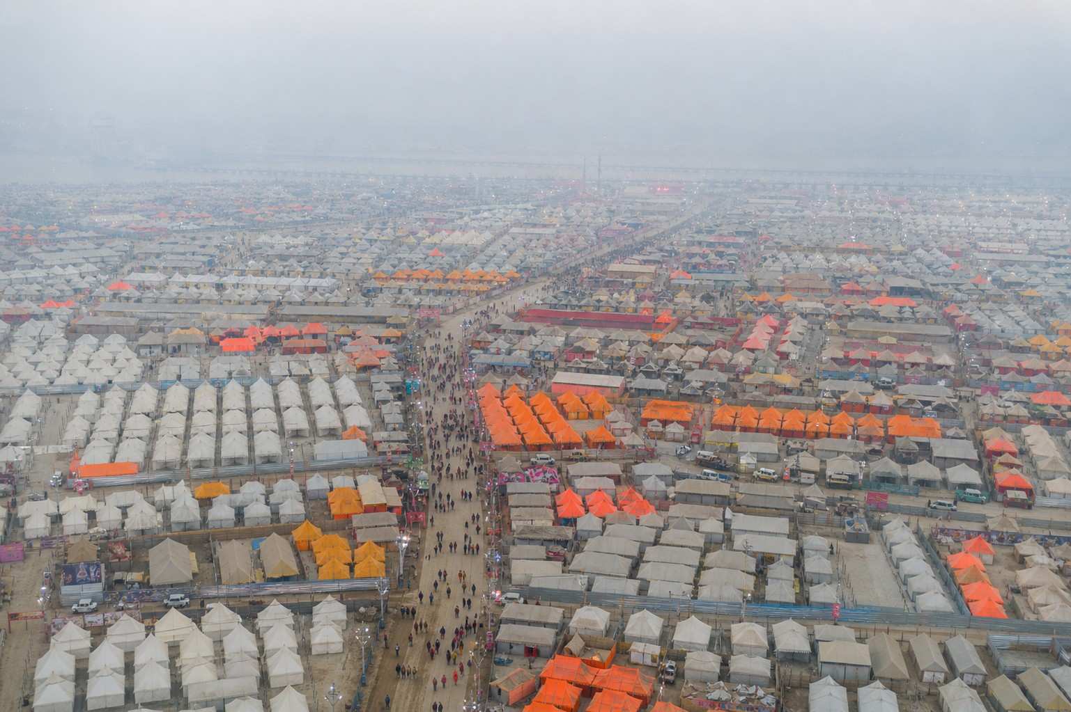 Aerial view of massive temporary tent city at Kumbh Mela grounds in Prayagraj with thousands of orange and white tents