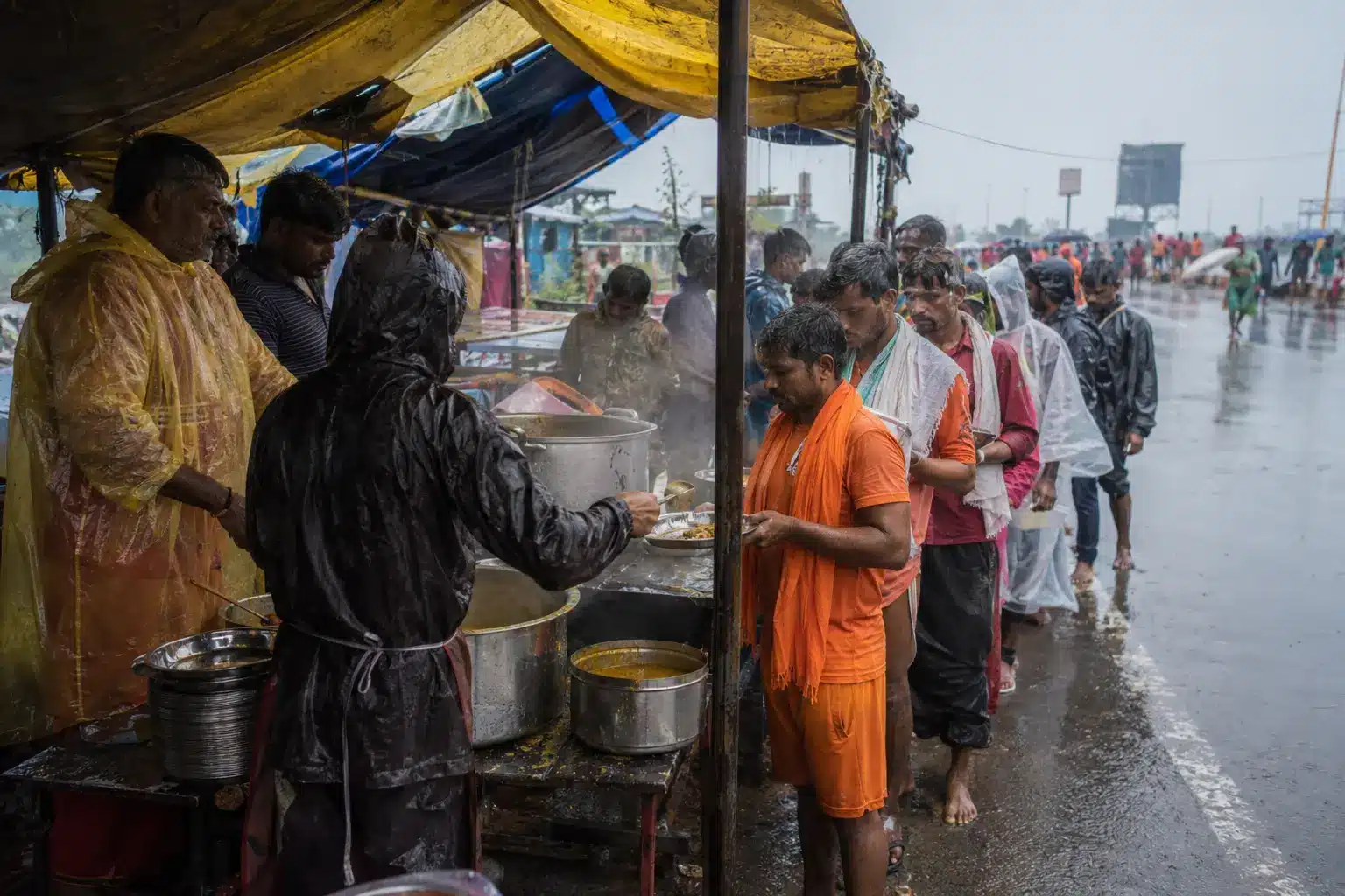 Volunteers serving free food to Kanwariyas at a monsoon roadside camp during Kanwar Yatra 2026