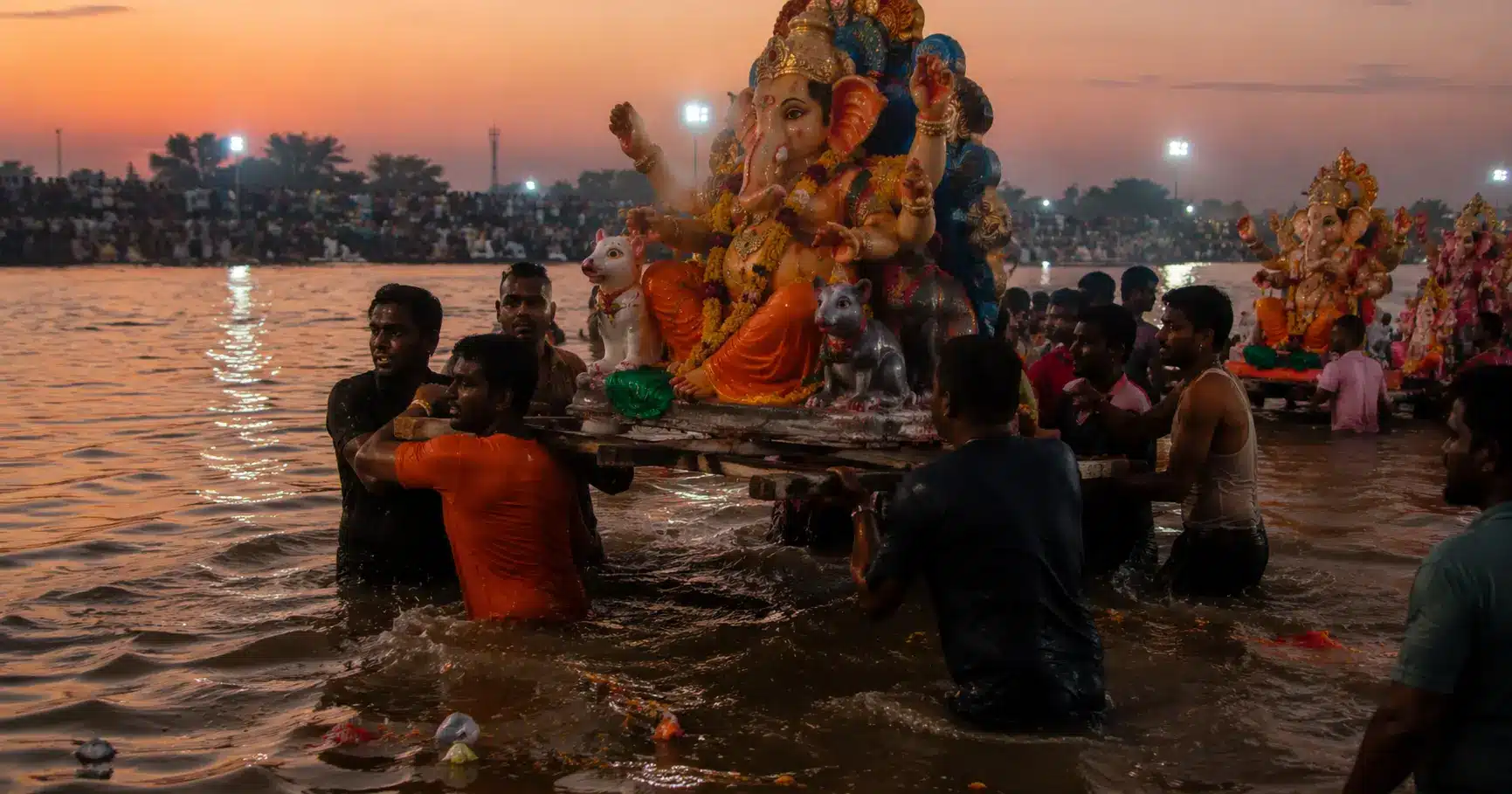 Devotees carrying a religious idol into a river for immersion during a festival