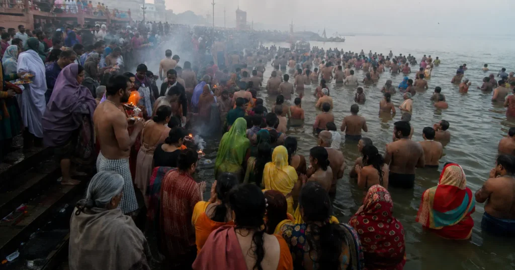 Thousands of devotees bathing together at a river ghat during a Hindu festival