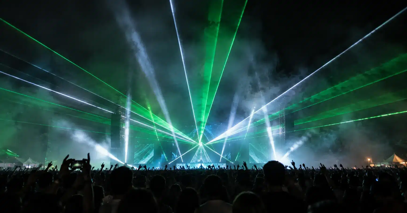 Laser beams cutting through fog above a crowd at a night festival