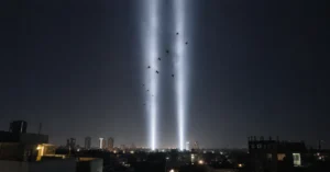 Birds circling within twin vertical beams of light rising into the night sky