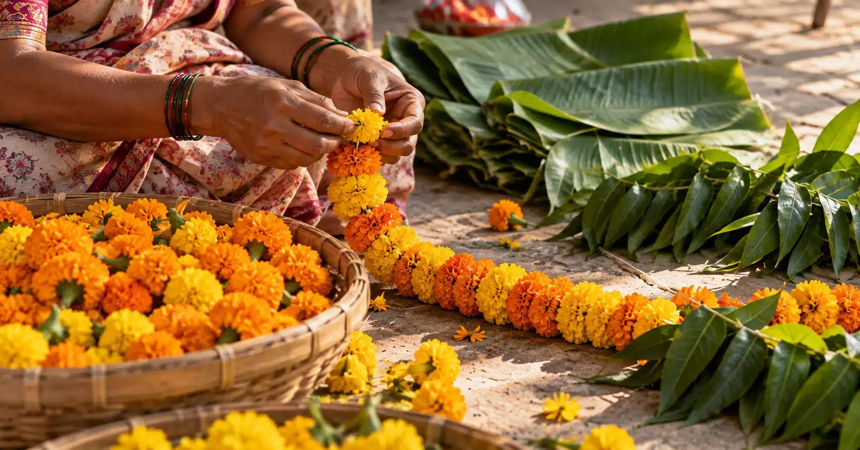 Hands threading a marigold garland alongside banana leaf decorations